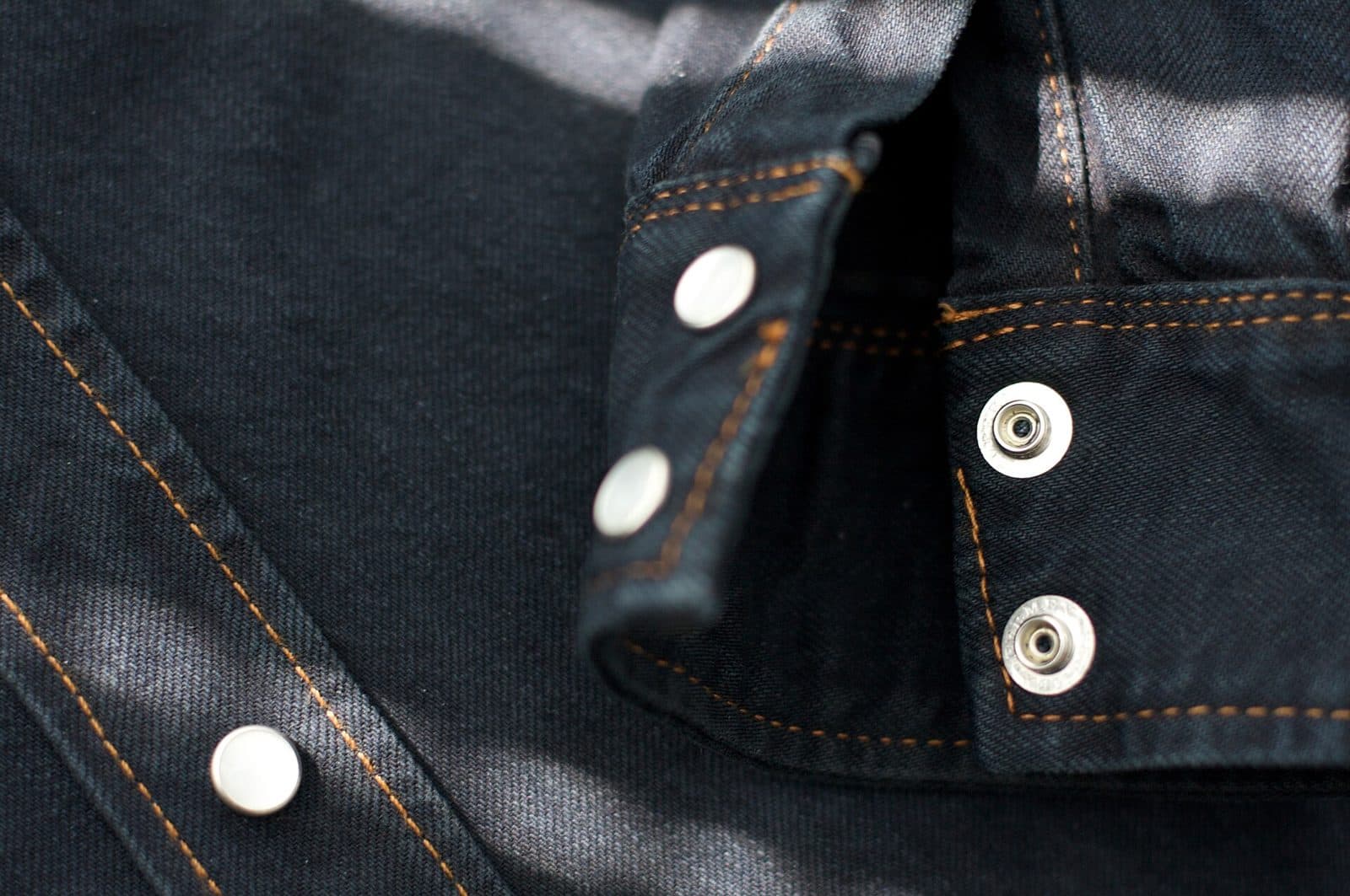 A denim jacket cuff and fastening detail. Check sleeve length and comfort while your elbows are bent