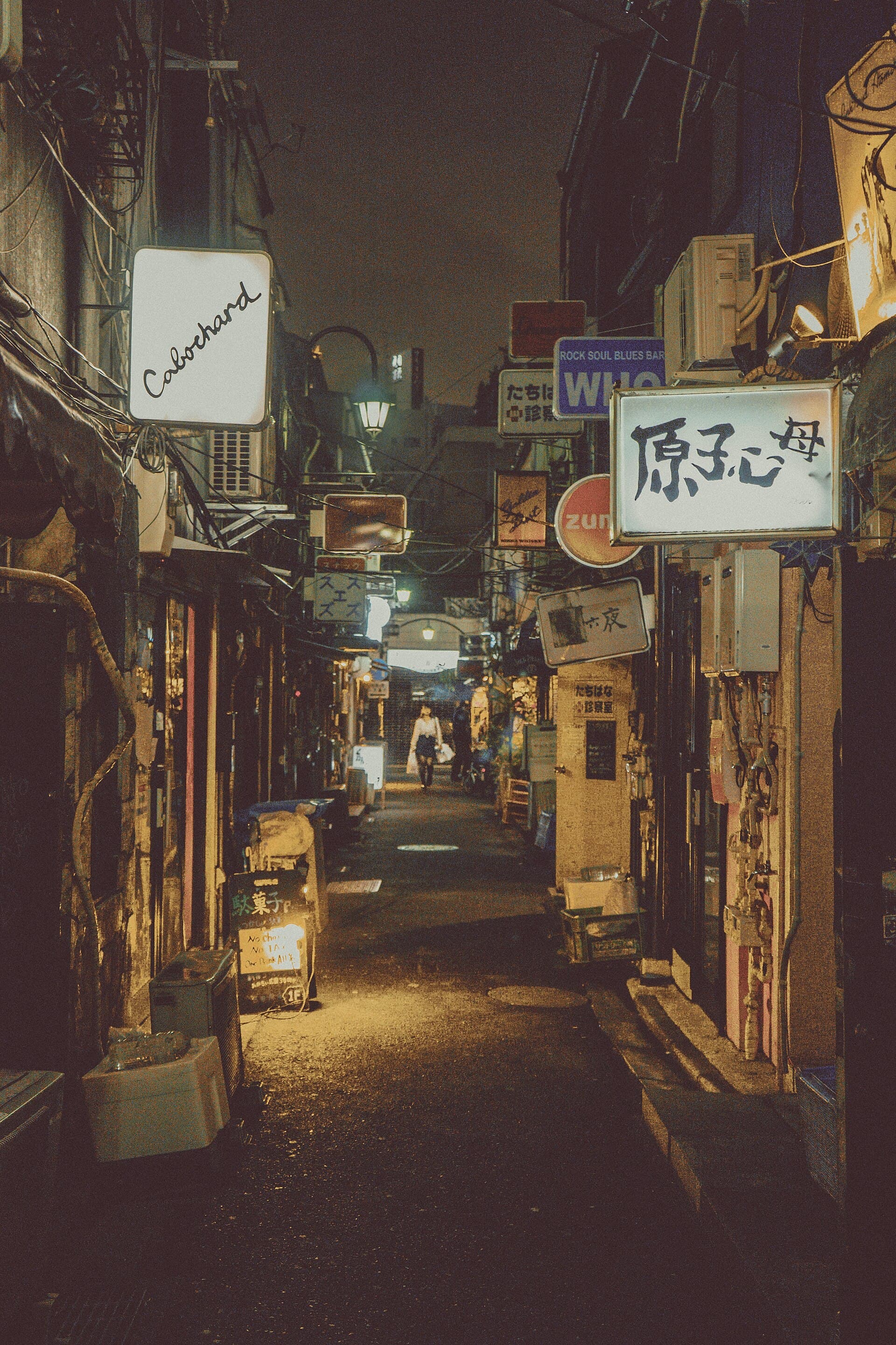 Intimate Golden Gai alley at night — neon, doors, and the scale before you push in