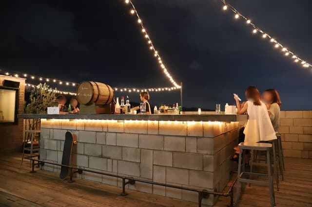 In The Moon rooftop — stone bar counter, festoon lights, and open-air stools above Gion