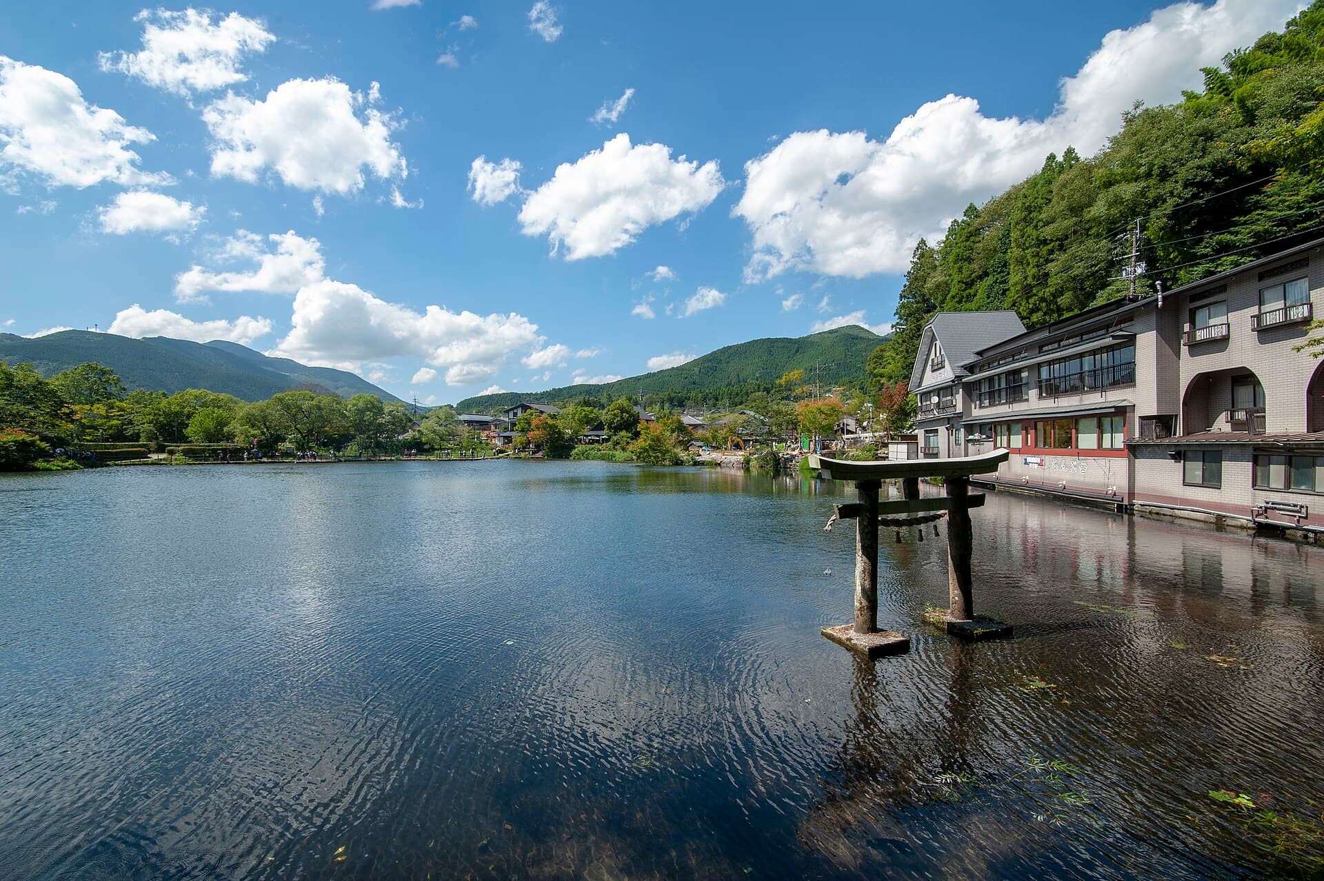 Lake Kinrin in Yufuin, with the torii gate standing in the water and Mount Yufu's foothills behind