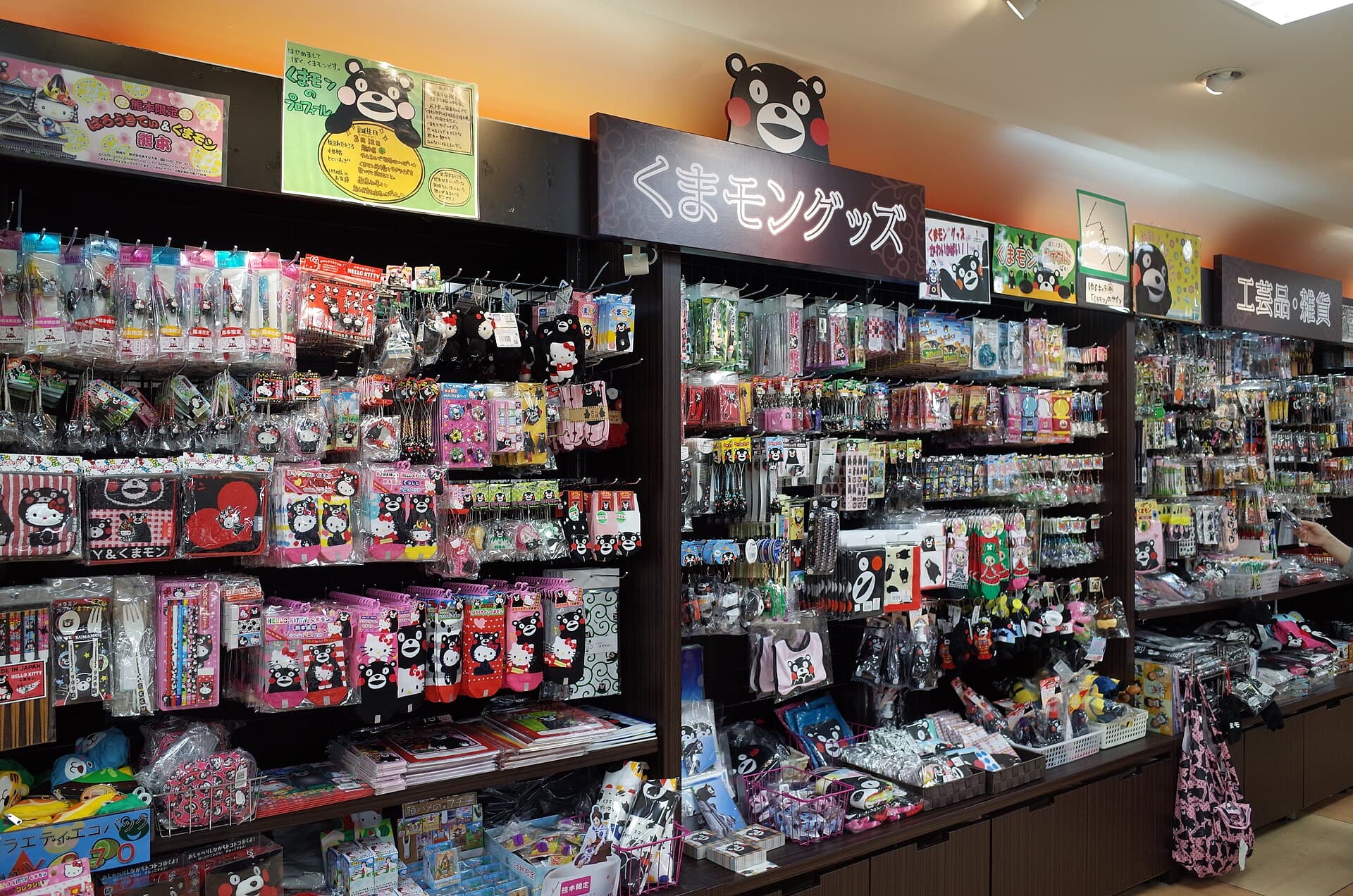 Kumamon merchandise on shelves at Kumamoto Airport, showing the black bear mascot's face on packaging and signage